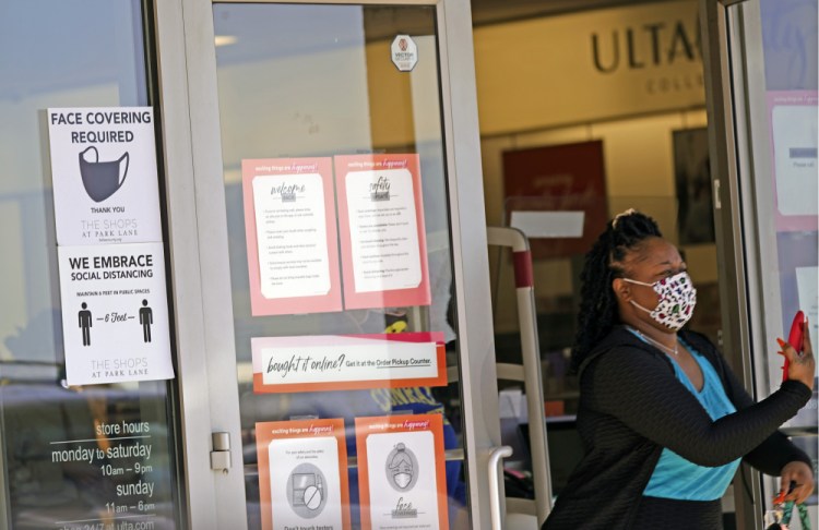 A customer exits a store with a mask required sign displayed, Tuesday, March 2, in Dallas.