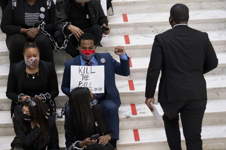 Protesters opposed to changes in Georgia's voting laws sit on the steps inside the State Capitol in Atlanta, Ga., as the Legislature meets Monday in Atlanta.