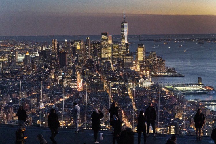 Visitors to the Edge, an outdoor observation deck 1100 feet above the ground, look at the lights of Manhattan, March 2, 2021, in New York. 