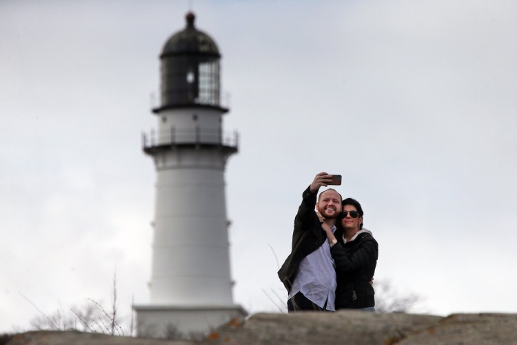 Dylan McKay and Vanessa Cremeans of Salt Lake City, Utah, take a selfie from Dyer Point with Cape Elizabeth Light in the background in this file photo from April. More than 10 million people traveled in Maine – either from out of state or another part of the state – between May and August, the height of the state's tourism season.