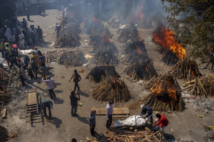 Multiple funeral pyres of victims of COVID-19 burn Saturday at a ground that has been converted into a crematorium for mass cremation in New Delhi, India.