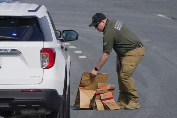 A sheriff's deputy from Frederick County, Md., puts paper bags with evidence into a police vehicle near the scene of a shooting at a business park in Frederick, Md., Tuesday, April 6. 