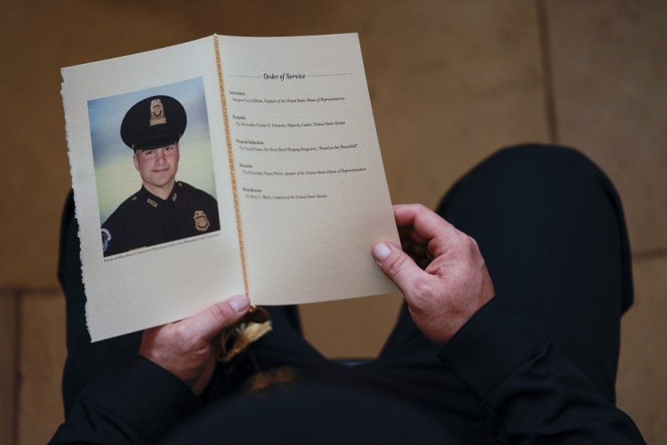 A U.S. Capitol Police officer holds a program during a ceremony memorializing U.S. Capitol Police officer Brian Sicknick on Feb. 3 at the Capitol Rotunda. The medical examiner's findings will likely inhibit the ability of federal prosecutors to bring homicide charges in Sicknick’s death.