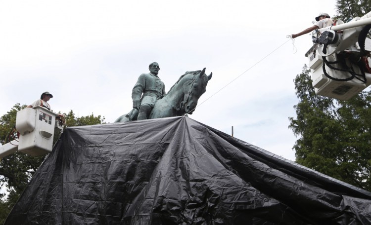 City workers drape a tarp over a statue of Confederate Gen. Robert E. Lee in Emancipation park in Charlottesville, Va. on Aug. 23, 2017. 