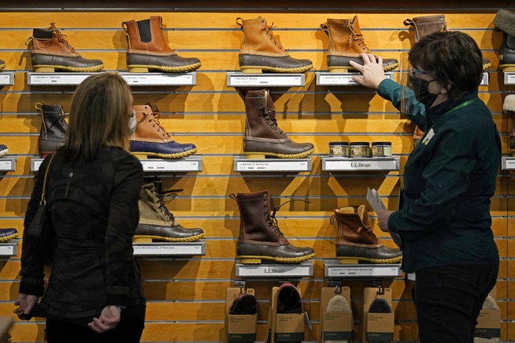 A salesperson helps a customer shopping for Bean Boots at the L.L. Bean flagship retail store in Freeport in March 2021.