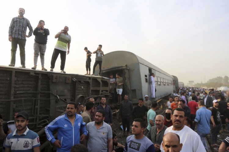 People gather at the site where a passenger train derailed injuring at least 100 people on Sunday in Banha, Egypt. 