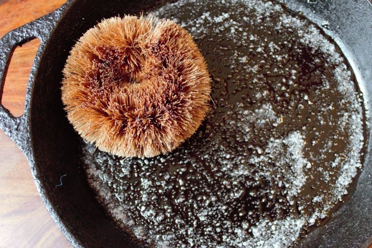 A coconut scouring pad with oil and salt tackles an 8-inch cast iron pan.