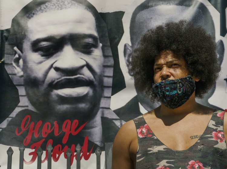 Actor Steven Thompson poses for a picture next to a poster of George Floyd in Los Angeles on Friday. Thompson is choosing not to watch the televised trial of Derek Chauvin, the white police officer charged in the death of George Floyd.


