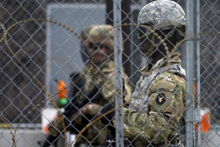 National Guard members are seen through fencing and wire near the Minneapolis Police 3rd Precinct in Minneapolis on Monday, after the murder trial against former Minneapolis police Officer Derek Chauvin advanced to jury deliberations.