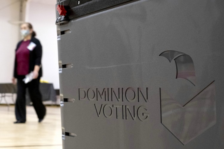 A worker passes a Dominion Voting ballot scanner while setting up a polling location at an elementary school in Gwinnett County, Ga., outside of Atlanta on Jan. 4, 2021. 
