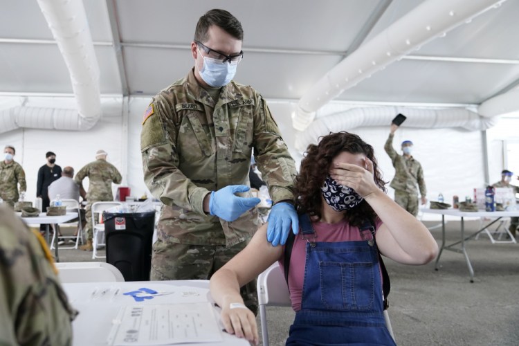 Leanne Montenegro, 21, covers her eyes because she doesn't like the sight of needles, while she receives the Pfizer COVID-19 vaccine at a FEMA vaccination center at Miami Dade College this month in Miami. FEMA has repeatedly reached out to other federal agencies for volunteers to help with the mass vaccination centers.