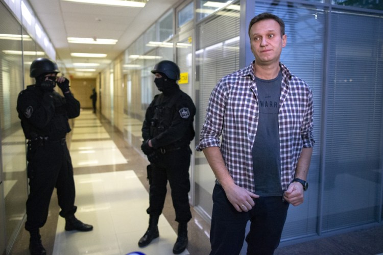Russian opposition leader Alexei Navalny speaks to the media in front of security officers standing guard at the Foundation for Fighting Corruption office in Moscow, Russia, on Dec. 26, 2019. 