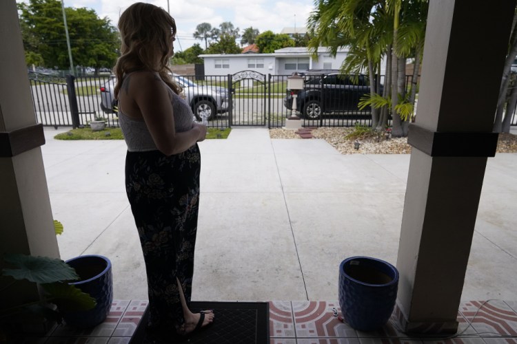 Nicole Russell looks out from her porch, on March 12 in Kendall, Fla. Because of the pandemic, she is  fearful of leaving her home and retreated to her bedroom for days at a time. 

