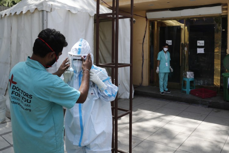 A health worker adjusts the face shield of another as she prepares to go inside a quarantine center for COVID-19 patients in New Delhi, India on April 19. 