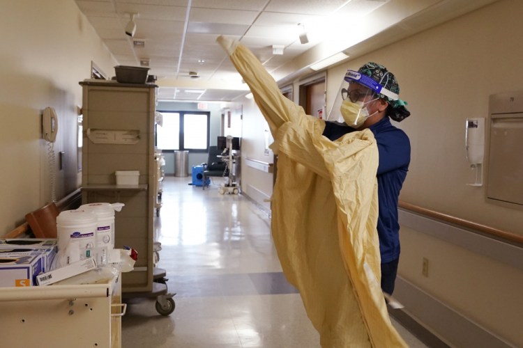 Registered Nurse Monica Quintana dons protective gear before entering a room at Beaumont Hospital on Wednesday in Royal Oak, Mich. Beaumont Health recently warned that its hospitals and staff had hit critical capacity levels. “A year ago, the phrase was tsunami,” said Dr. Paul Bozyk, the hospital's assistant chief of critical care and pulmonary medicine.