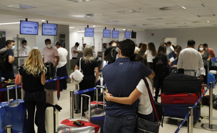People check in for a flight on Saturday to Miami at Silvio Pettirossi Airport in Luque, Paraguay. A lack of supply in many Latin American countries has residents of means coming to the U.S. to get their doses. Miami was a popular destination until Florida officials began requiring proof of residency. 