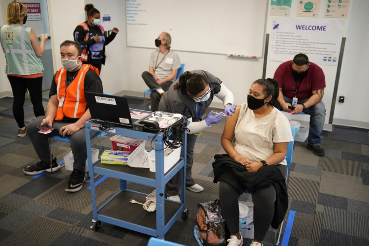 Registered nurse Rocio Ortiz administers a vaccine for workers at an Amazon Fulfillment Center on March 31 in Las Vegas. A growing number of companies and labor unions are directly securing coronavirus vaccines for their workers. It also opened on-site clinics in Kansas and Missouri. 