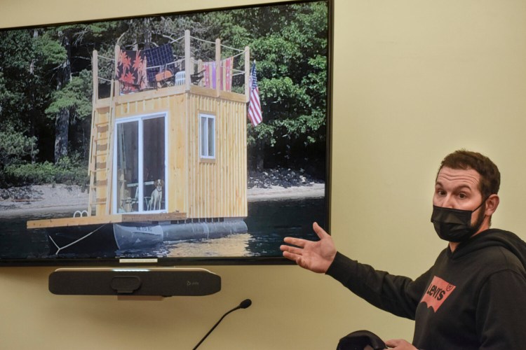 Jason Spinney, half owner of the pontoon-style floating structure pictured on the screen, speaks to city councilors and Green Lake shorefront property owners on April 19.