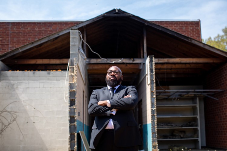 Pastor Kenneth Robinson stands in front of a section of Briar Creek Road Baptist Church in Charlotte, N.C., that was set on fire in 2015. MUST CREDIT: Photo for The Washington Post by Logan Cyrus