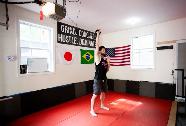 Austin Miller, chef and owner of Mami, works out with a kettlebell in his home gym on a recent May day. Miller built a home gym in his garage during the pandemic to alleviate stress and says he is in the best shape of his life now. 