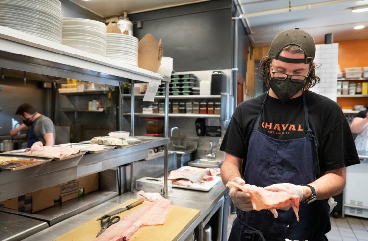 PORTLAND, ME - MAY 26: Kirby Sholl, chef de cuisine at Chaval, shows a section of halibut ribs to Christine Burns Rudalevidge after he cut them out of a halibut at the restaurant on Wednesday, May 26, 2021. (Staff photo by Gregory Rec/Staff Photographer)