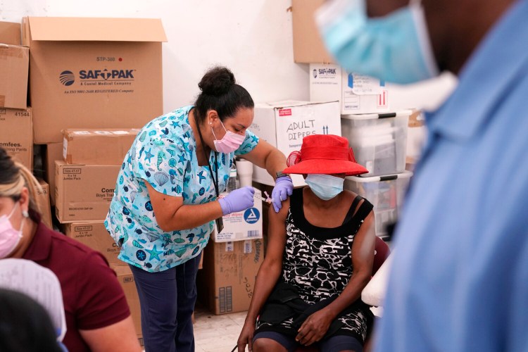 FILE - In this April 10, 2021, file photo, registered nurse Ashleigh Velasco, left, administers the Johnson & Johnson COVID-19 vaccine to Rosemene Lordeus, right, at a clinic held by Healthcare Network in Immokalee, Fla. Fewer Americans are reluctant to get a COVID-19 vaccine than just a few months ago, but questions about side effects and how the shots were tested still hold some back, according to a new poll that highlights the challenges at a pivotal moment in the U.S. vaccination campaign. (AP Photo/Lynne Sladky, File)