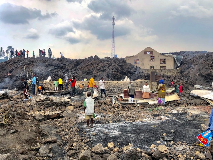People gather on a stream of cold lava rock following the overnight eruption of Mount Nyiragongo in Goma, Congo, Sunday, May 23, 2021. The volcano unleashed lava that destroyed homes on the outskirts of Goma but the city of nearly 2 million people was mostly spared after the nighttime eruption. Residents of the Buhene area said many homes had caught fire as lava oozed into their neighborhood. (AP Photo/Clarice Butsapu)