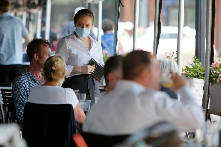 A server prepares to take an order from customers seated outside at Legal Sea Foods, Wednesday, May 26, 2021, in Boston. (AP Photo/Mary Schwalm)