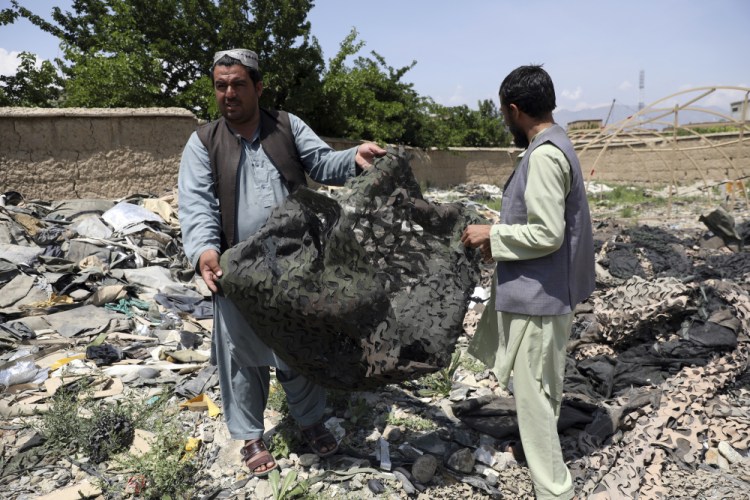 Afghan men hold scraps of tenting at a scrapyard outside Bagram Air Base, northwest of Kabul, Afghanistan, on Monday. 