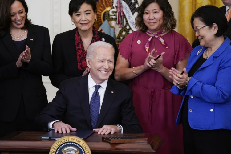 President Biden smiles after signing the COVID-19 Hate Crimes Act, in the East Room of the White House on Thursday in Washington. Top row from left, Vice President Kamala Harris, Rep. Judy Chu, D-Calif., Rep. Grace Meng, D-N.Y., and Sen. Mazie Hirono, D-Hawaii. 