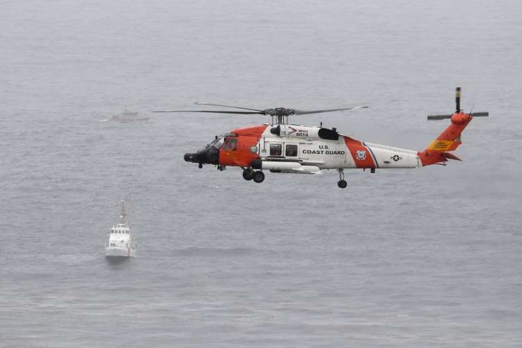 A U.S. Coast Guard helicopter flies over boats searching the area where a boat capsized just off the San Diego coast on Sunday. Authorities believe everyone is accounted for but continued to search. 