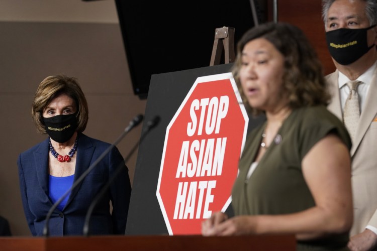 House Speaker Nancy Pelosi of Calif., left, listens as Rep. Grace Meng, D-N.Y., center, speaks during a news conference on Capitol Hill in Washington, Tuesday, May 18, on the COVID-19 Hate Crimes Act. Rep. Mark Takano, D-Calif., listens at right. 