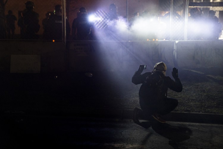 Police shine lights on a demonstrator with raised hands during a protest outside the Brooklyn Center Police Department in Brooklyn Center, Minn., over the fatal shooting of Daunte Wright, on April 14. The American Civil Liberties Union of Minnesota called the proposal “an important first move” in changing policing. 