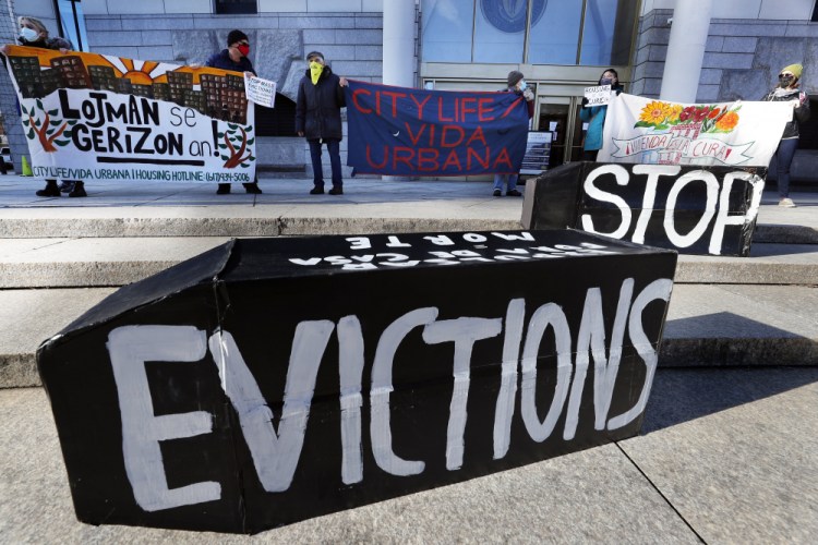Demonstrators hold signs in front of the Edward W. Brooke Courthouse in Boston on Jan. 13, 2021. 