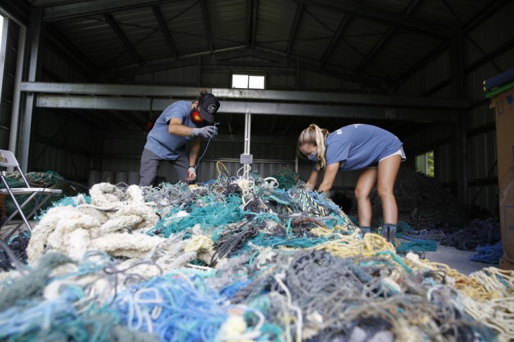 Hawaii Pacific University graduate student Drew McWhirter, left, and Raquel Corniuk, a research technician at the university's Center for Marine Debris Research, pull apart a massive entanglement of ghost nets on May 12 in Kaneohe, Hawaii.