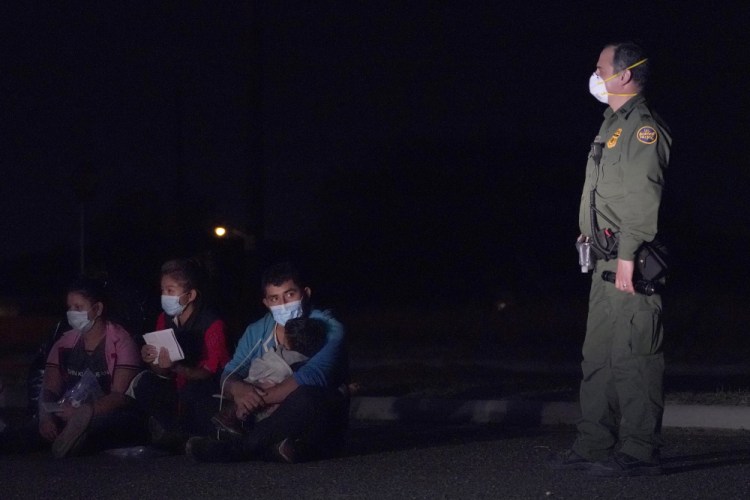 Migrants wait with at a U.S. Customs and Border Protection agent at an intake area after crossing the U.S.-Mexico border on March 24 in Roma, Texas. A new report found at least 348 cases in which Immigration and Customs Enforcement had no records showing migrants wanted to leave their children in the U.S.


