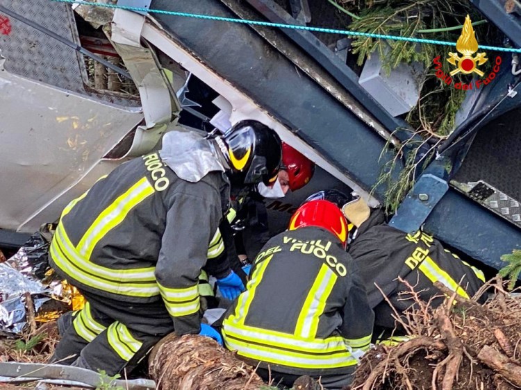 Rescuers work by the wreckage of a cable car after it collapsed Sunday near the summit of the Stresa-Mottarone line in the Piedmont region, northern Italy.