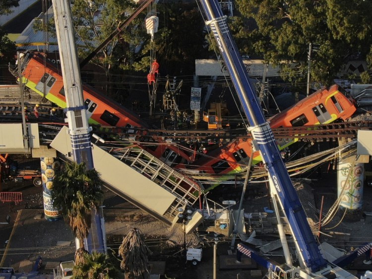 An aerial view of subway cars dangle at an angle from a collapsed elevated section of the metro, in Mexico City, Tuesday, May 4, 2021. The elevated section collapsed late Monday killing at least 23 people and injuring at least 79, city officials said. 
