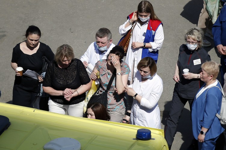 Medics and friends help a woman board an ambulance at a school after a shooting in Kazan, Russia, Tuesday, May 11. 