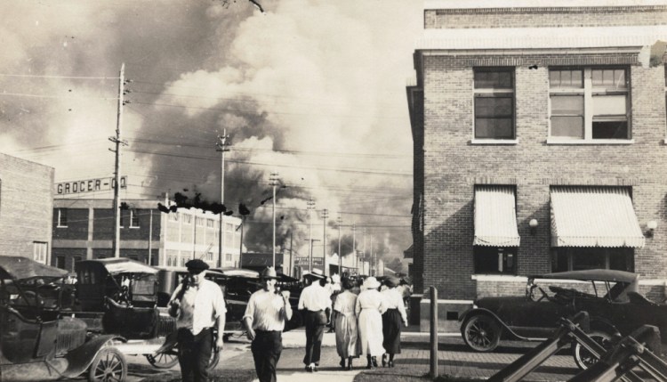Two armed men walk away from burning buildings as others walk in the opposite direction during the June 1, 1921, race massacre in Tulsa, Okla. 

