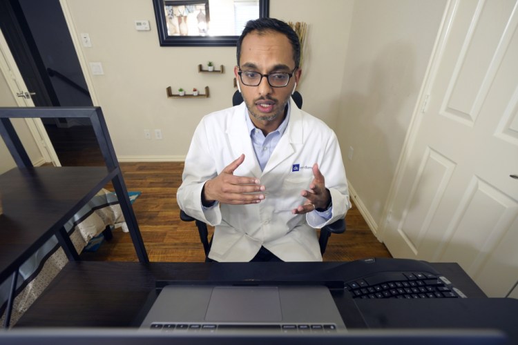 Medical director of Doctor on Demand Dr. Vibin Roy speaks to a patient during an online primary care visit from his home Friday in Keller, Texas.