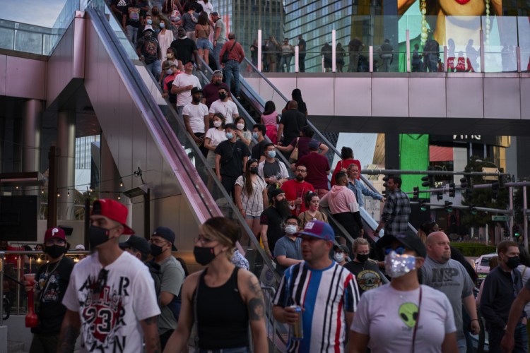 People ride an escalator along the Las Vegas Strip on April 24. The city is bustling again after casino capacity limits were raised to 80 percent. 