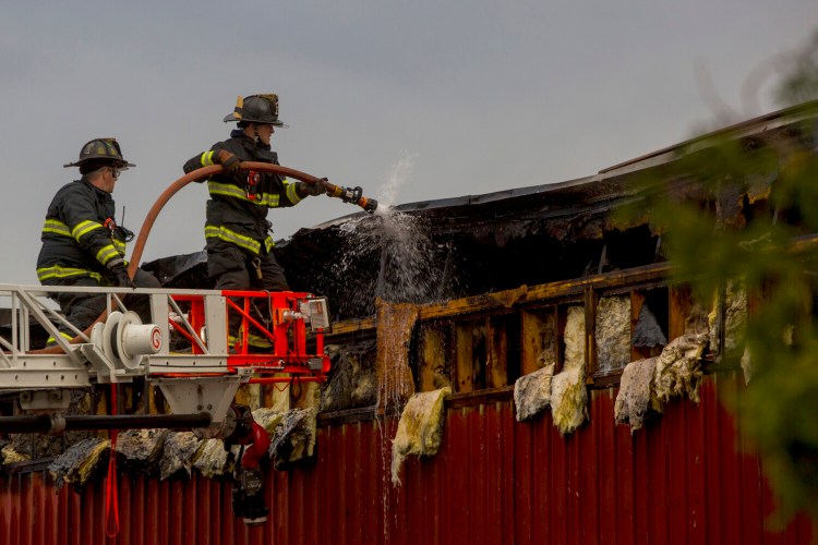 Firefighters cleanup after an early morning fire at 160 Presumpscot Street in Portland on Friday. 
