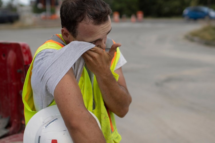 Trent Cullinan of Sargent Corporation wipes sweat from his face while taking a break from construction work on Preble Street Extension on Tuesday.