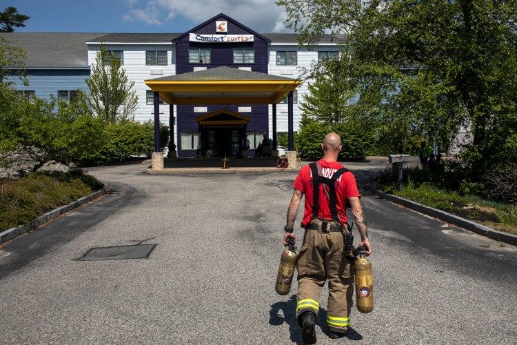 FREEPORT, ME - JUNE 29: A Yarmouth firefighter carries two SCBA bottles in for firefighters who were entering the Comfort Suites after it was evacuated due to high carbon monoxide levels inside the hotel in Freeport on Tuesday, June 29, 2021. A water heater malfunction is believed to have been the cause of the leak that sent three people to the hospital. (Staff photo by Brianna Soukup/Staff Photographer)
