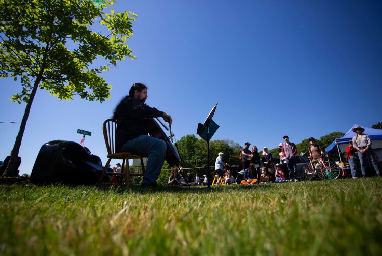 John Ott of Portland sits in the shade of a tree as he plays the cello at a farmers market in Payson Park on Saturday. The performance was part of the Portland Bach Experience.