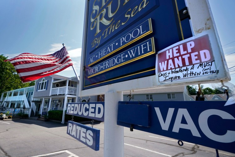A "help wanted" sign is taped to a sign outside a motel Wednesday, May 26, 2021, in Wells, Maine. America’s tourist destinations are facing a severe worker shortage just as they’re trying to rebound from a devastating year lost to the pandemic. (AP Photo/Robert F. Bukaty)