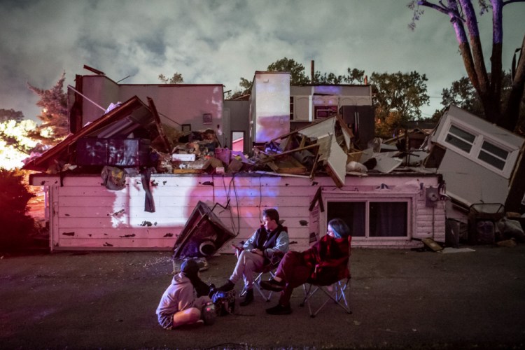 Bridget Casey sits in the driveway of her severely damaged home with her son Nate, 16, and daughter Marion, 14, after a tornado swept through the area in Woodridge, Ill., early Monday morning. 