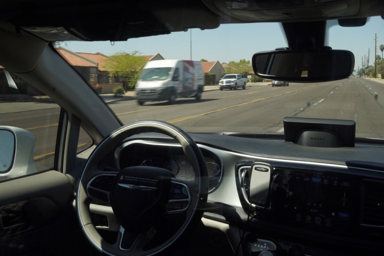An autonomous Waymo minivan moves along a city street in Chandler, Ariz.