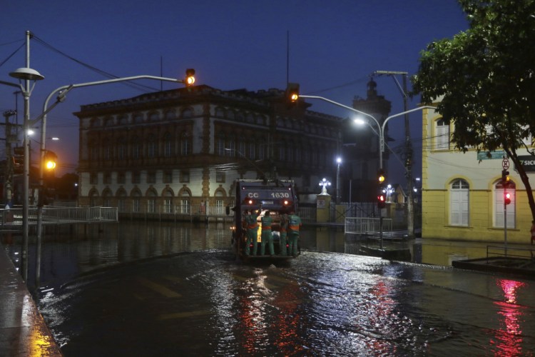 City workers ride on the back of a garbage truck navigating through a street flooded by the Negro River, in downtown Manaus, Amazonas state, Brazil, on Tuesday.

